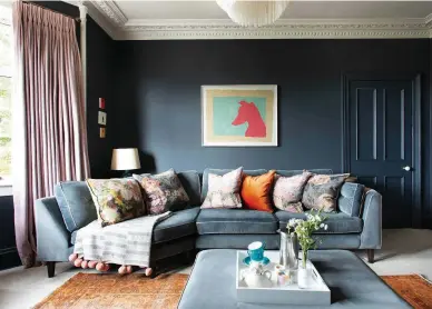 ??  ?? Carley has softened the dark, dramatic blue in her living room with delicate pinks and rich rusts, punctuated by punchy brights like her Julian Chichester print – a gift from one of Carley’s interior design clients in honour of the family’s whippet, Red
