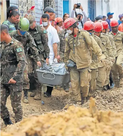  ?? AP ?? Asistencia. Bomberos y soldados retiran el cuerpo de una víctima de los deslaves en la zona de Recife.