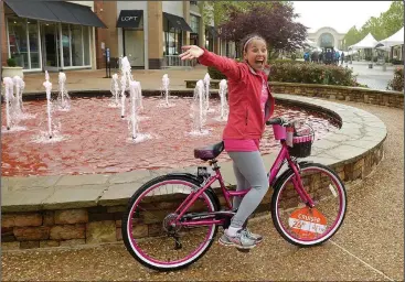  ?? NWA Democrat-Gazette/BEN GOFF • @NWABENGOFF ?? Gloria Flores Passmore of Rogers, a breast cancer survivor for nearly six years, waves to a friend after picking up the Susan G. Komen-themed Kent bicycle she won in a drawing Saturday during the annual Susan G. Komen Ozark Race for the Cure at...