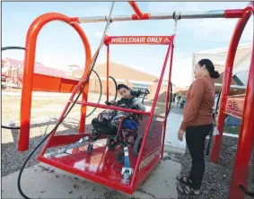  ?? (NWA Democrat-Gazette/J.T. Wampler) ?? Doreka Edwin watches Monday as her son, Dion, swings on a wheelchair swing at Sonora Elementary School in Springdale. The swing has four wheelchair tie-downs to secure the chair when the swing rocks and also has a rope for the students to self-propel. Visit nwaonline.com/photo for today’s photo gallery.