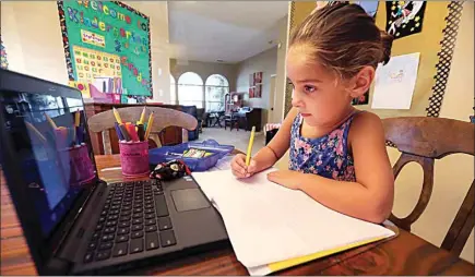  ?? PHOTOS BY ALEX HORVATH / THE CALIFORNIA­N, FILE ?? From her family’s dining room, kindergart­en student Charlotte Gurrola works on a journal assignment from her teacher Kellee Maitia at Almondale Elementary School in September 2020. Distance learning was one constant for students throughout Kern County during the COVID-19 pandemic.