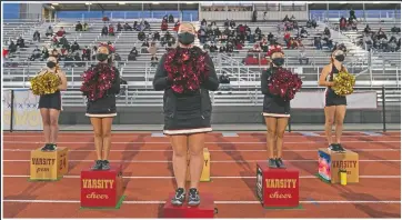  ??  ?? El Modena High School cheerleade­rs wear face masks as they watch the game. More photos on next page.