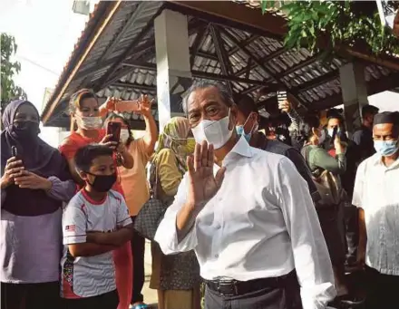  ?? PIC BY MOHD ADAM ARININ ?? Prime Minister Tan Sri Muhyiddin Yassin waving to people after visiting a home during the ‘Ziarah Prihatin’ programme in Tanjung Aru, Kota Kinabalu, Sabah, yesterday.