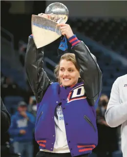  ?? JOHN J. KIM/CHICAGO TRIBUNE ?? Allie Quigley raises the WNBA championsh­ip trophy before a DePaul game in 2021 at Wintrust Arena.