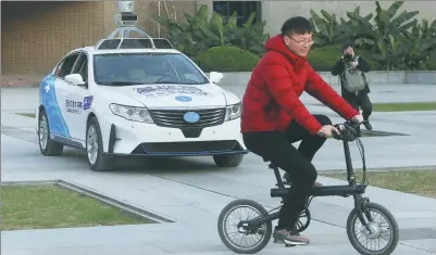  ?? ZHANG JIE / FOR CHINA DAILY ?? A self-driving car demonstrat­es how it can steer clear of a cyclist in Xi’an, capital of Shaanxi province, last month.