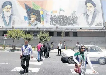  ?? Atta Kenare AFP/Getty Images ?? A BILLBOARD depicting Iran’s supreme leader, Ali Khamenei, left, and the late Ayatollah Ruhollah Khomeini provides a backdrop for pedestrian­s in Tehran. Khomeini’s tomb was the site of a terrorist attack.