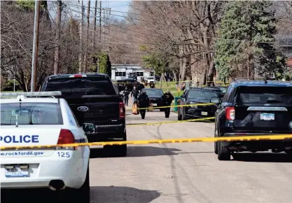  ?? ?? ABOVE: An officer carries a bag of evidence from the crime scene after multiple stabbings left four dead and seven injured on March 27 near Cleveland Avenue in Rockford.