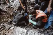  ?? Mohammed Dahman/Associated Press ?? Rescuers try to pull a boy from a destroyed building Thursday after an airstrike in the Bureij refugee camp in the Gaza Strip.