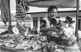  ??  ?? Marida Siboya sells cuts of pork in North Sumatra. Many Batak families, who are Christian, raise pigs, an anomaly in the country.