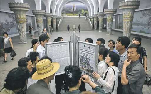  ?? Ed Jones/AFP/Getty Images ?? Commuters gather around a newspaper — featuring stories about North Korean leader Kim Jong Un meeting with President Donald Trump — on a subway platform Wednesday in Pyongyang North Korea.