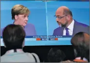  ?? AP/MICHAEL SOHN ?? People watch the live televised debate of German Chancellor Angela Merkel (on screen, left) and Social Democrat Party chairman and challenger Martin Schulz on Sunday at a television studio in Berlin.