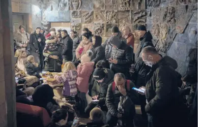  ?? BERNAT ARMANGUE/AP ?? People take refuge in a basement that is being used as a bomb shelter on Saturday in Lviv, Ukraine.