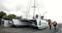  ?? PHOTO: MARTIN DE RUYTER/STUFF ?? Contractor­s discuss how to get the Stray Cat catamaran off the Nelson road where it washed up during a storm.