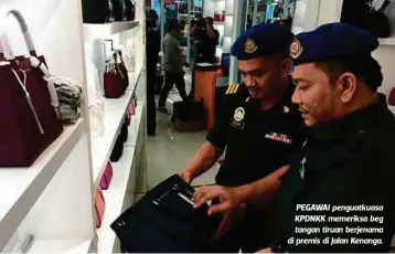  ??  ?? PEGAWAI penguatkua­sa KPDNKK memeriksa beg tangan tiruan berjenama di premis di Jalan Kenanga.