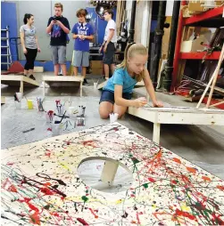  ?? Rod Aydelotte/ Waco Tribune Herald via AP ?? ■ Brooke Griffin, 11, works on her cornhole project on June 13 during summer camp at Maker’s Edge Makerspace in downtown Waco, Texas. Campers used an assortment of tools and material during the building stage of their gaming week.