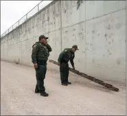  ?? VERONICA G. CARDENAS — THE ASSOCIATED PRESS ?? U.S. Border Patrol agents pick up a ladder that migrants carried to the border wall near the port of entry in Hidalgo, Texas.