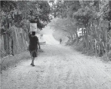  ?? PEDRO QUINTERO ?? > Una mujer recorre un largo camino para llevar agua a su hogar.