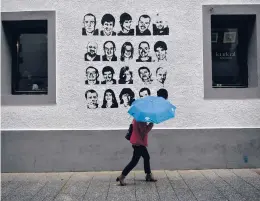  ?? AP 2018 ?? A woman walks past a wall painted with portraits of prisoners of the Basque separatist group ETA, in Hernani, Spain. The U.S. is poised to remove the group from a blacklist.