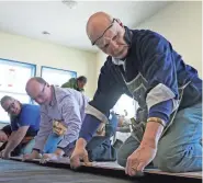  ?? RICK WOOD / MILWAUKEE JOURNAL SENTINEL ?? Bill McTeer and other Habitat volunteers snap in flooring for a new home. Milwaukee focuses its program on one area at a time, but the Twin Cities takes a regional approach.