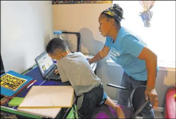  ?? Michael Rubinkam The Associated Press ?? Tiffany Shelton helps son P.J. Shelton, 7, a second grader, during an online class Sept. 3 at their home in Norristown, Pa. The district plans to offer online-only instructio­n.