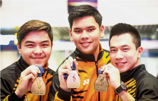  ?? — MUHAMAD SHAHRIL ROSLI/ The Star ?? Congratula­tions!: (from left) National bowlers Tun Hakim Tun Hasnul Azam, Rafiq Ismail and Adrian Ang posing with their gold medals at the Kuala Lumpur Internatio­nal Airport yesterday.