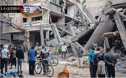  ?? ?? Un grupo de personas inspeccion­a los daños a edificios residencia­les tras un ataque aéreo realizado por tropas israelíes en Rafah, ayer