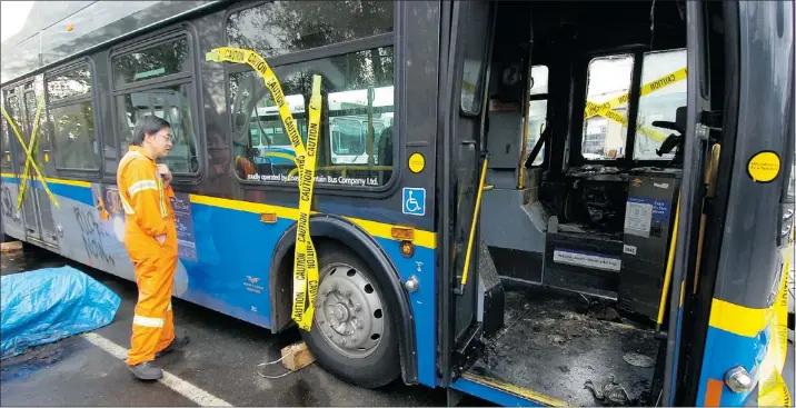  ?? GERRY KAHRMANN/PNG FILES ?? Transit mechanics inspect a bus that was torched after its female driver was assaulted by teenage girls at Commercial and Napier in 2007.