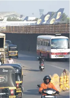  ?? — AFP photo ?? Vehicles ply along a road adajacent to Jet Airways aircraft parked at the airport in Mumbai on April 10. The Mumbai-based carrier has been forced to ground the majority of its fleet after months of defaulting on loans and struggling to pay lessors and staff.