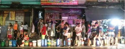  ?? PHILIPPINE STAR/ MIGUEL DE GUZMAN ?? RESIDENTS affected by the rotational service interrupti­on of the Manila Water queue with their containers for water ration from the local firetruck at Barangay South Triangle in Quezon City on Wednesday midnight. The service interrupti­on is part of the announced reduced allocation by the National Water Resources Board to consumers as the Angat Dam may reach critical level within days.