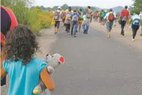  ?? REBECCA BLACKWELL/ASSOCIATED PRESS ?? A girl carries a teddy bear as she walks with her mother with a migrant caravan Saturday near Arriaga, Mexico. The walk is harder on parents and their kids.