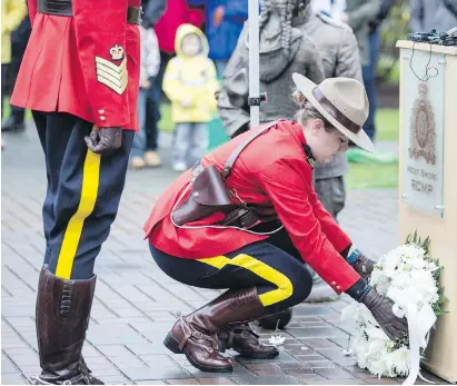  ??  ?? RCMP Const. Elyse Patten lays a wreath at a remembranc­e ceremony for Const. Sarah Beckett in front of the West Shore detachment on Wednesday.