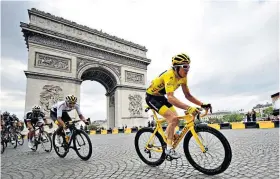  ??  ?? Lap of honour: Geraint Thomas en route to Tour de France victory, and (below) jokily celebratin­g with wife Sara and some Welsh cakes