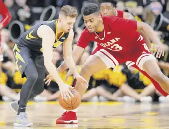  ?? Charlie neibergall / Associated Press ?? iowa guard Jordan Bohannon, left, picks up a loose ball in front of indiana forward Juwan morgan during the first half of an NCAA college basketball game on friday night in iowa City, iowa. Bohannon had 17 points, including some clutch 3-pointers in ot for iowa.