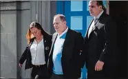  ?? MARK KAUZLARICH, BLOOMBERG ?? Movie producer Harvey Weinstein is escorted in handcuffs out of the New York Police Department 1st Precinct on Friday after surrenderi­ng to face charges in sexual assault cases involving two women.
