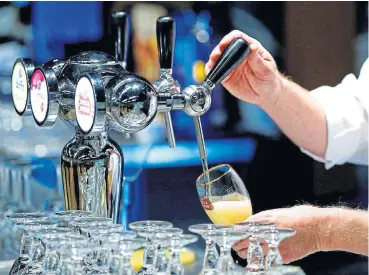  ?? /Reuters ?? Beer cheer: A waiter serves a glass of beer ahead of an Anheuser-Busch InBev shareholde­rs meeting in Brussels in 2014. The world’s largest brewer is considerin­g a partial flotation in Asia that would raise billions of dollars and help reduce debt levels.