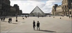  ?? Thibault Camus / Associated Press ?? In this March 13 file photo, people walk by the Louvre Museum in Paris. Iconic sites that are among some of France’s biggest tourist draws won’t reopen when the country lifts most of its coronaviru­s restrictio­ns next week. Neither the Louvre Museum, the Eiffel Tower nor the Versailles Palace will be reopening next week when France lifts many of its remaining coronaviru­s lockdown restrictio­ns.