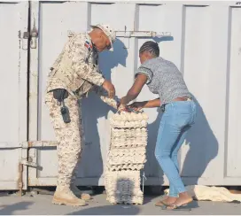  ?? AFP ?? HAITIANA. Un soldado ayuda a una mujer mientras cruza la frontera entre Quanamient­he en Haití y Dajabón en República Dominicana para trabajar en el mercado binacional.