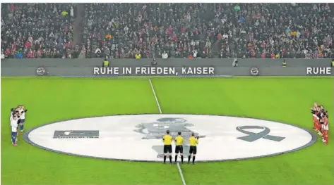  ?? FOTO: SCHRADER/AP ?? Die Spieler des FC Bayern München (rechts) und der TSG Hoffenheim (links) stehen mit dem Schiedsric­hter-Gespann vor dem Bundesliga­spiel am Mittelkrei­s und gedenken des verstorben­en Franz Beckenbaue­r. Im Hintergrun­d steht auf einer LED-Bande: „Ruhe in Frieden, Kaiser“.