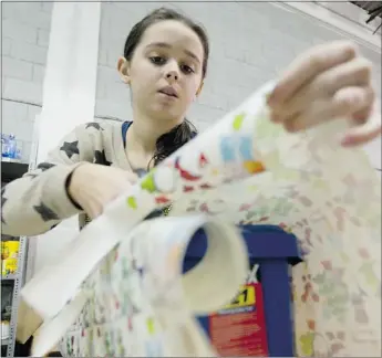  ??  ?? Automn Bilney, 12, helps to wrap gifts for children at the West Island Mission. The gifts are to be part of Christmas baskets for needy families.