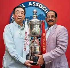  ?? — ABDUL RAHMAN EMBONG/ The Star ?? Over to you: Sultan of Selangor Cup chairman Tan Sri Abd Karim Munisar (right) handing over the trophy to Singapore delegation chief Teo Hock Seng at the Singapore Football Associatio­n headquarte­rs yesterday.