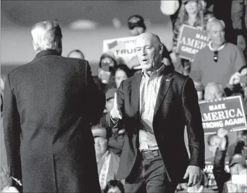  ?? CAROLYN KASTER/AP ?? U.S. Rep. Greg Gianforte, R-Mont., right, greets President Donald Trump during a rally Thursday in Missoula, Mont. Trump praised Gianforte for his 2017 assault of a reporter.