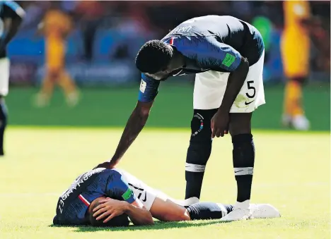  ?? GETTY IMAGES ?? Lucas Hernandez is comforted by teammate Samuel Umtiti after suffering an injury in France’s opening World Cup match against Australia last weekend. Hernandez was heavily involved in France’s attack, but he also rolled round on the pitch at every...