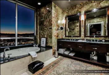  ?? Ivan Sher Group ?? The spa-like master bath showcases multicolor­ed granite-esque stone walls, soaking tub with a view of the Strip, walk-in shower and dual vanities.