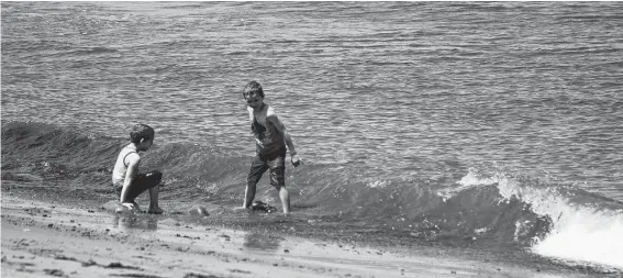  ?? NICOLE SULLIVAN/CAPE BRETON POST ?? Seven-year-old Liam Daley braces for the wave as his brother Kohen, 6, laughs on the shore. Both were excited to be playing in the waves at Dominion Beach on Friday although it seemed neither went as far as dunking their heads completely under.