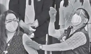  ?? AP/AARON FAVILA ?? HEALTH Secretary Francisco Duque III prepares to inject China’s Sinovac vaccine on Filipino doctor Eileen Aniceto at the Lung Center of the Philippine­s in Quezon City on March 1, 2021.