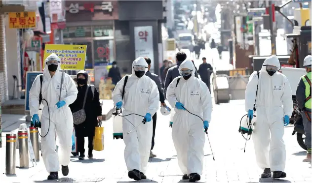  ?? Associated Press ?? ↑
South Korean soldiers wearing protective gears spray disinfecta­nt as a precaution against the new coronaviru­s in Seoul on Thursday.