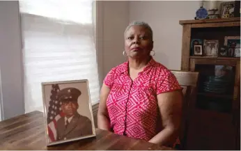  ?? ANTHONY VAZQUEZ/SUN-TIMES ?? Pamela Redd sits near a photo of her brother Carl Redd as a young man at her home in Lawndale. Carl Redd worked for decades at Sears and had a “Cheshire cat”-wide grin, according to his family.