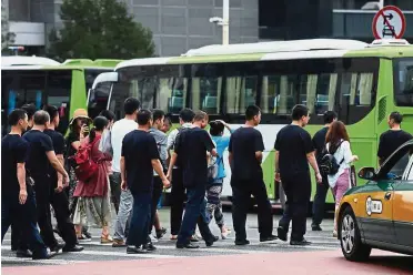  ?? — AFP ?? No protest allowed: Petitioner­s are escorted to a bus by security personnel before being driven away in Beijing last Monday. Hundreds of police swarmed the streets of Beijing’s financial district as Chinese authoritie­s aggressive­ly quashed a planned protest against losses sustained by P2P lending platforms.