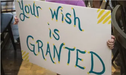  ?? ?? A girl holds a sign while waiting for her cousin to arrive for a surprise Make-A-Wish announceme­nt. Photograph: Ben Goff/AP