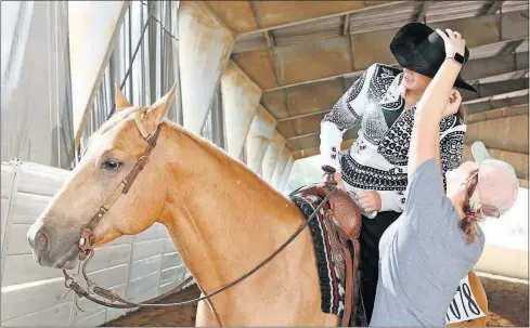  ?? [BARBARA J. PERENIC/DISPATCH PHOTOS] ?? Lindsey Bicknell uses bobby pins to secure the hat of Bailie Young, of Gallopolis, before a youth reining competitio­n at the All America Quarter Horse Congress on Saturday at the Ohio Expo Center.